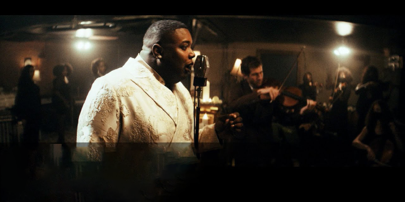 Jacob Lusk in a tux singing into a microphone